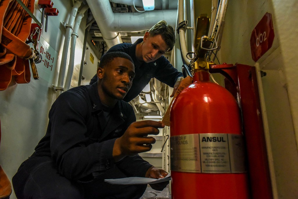 Engineers inspecting a large fire extinguisher against a checklist